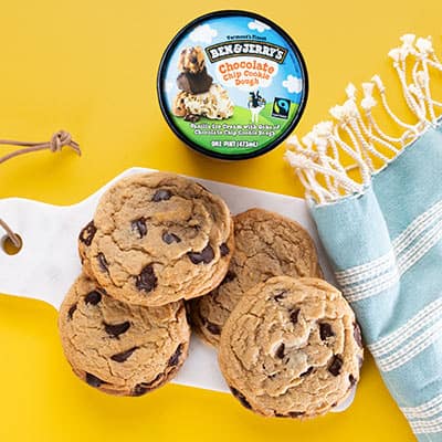 Cookies on a cutting board with a pint of Ben & Jerry's Chocolate Chip Cookie Dough ice cream.