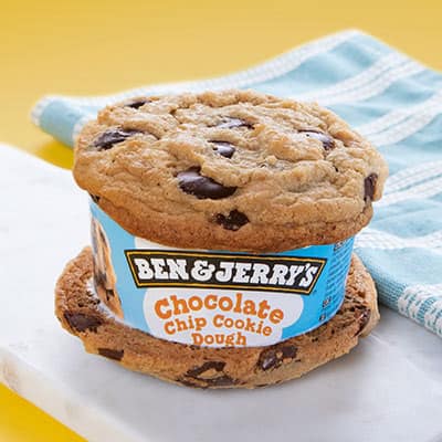 Ben & Jerry's ice cream sandwich on a cutting board. Ice cream label shows that it is Chocolate Chip Cookie Dough ice cream.